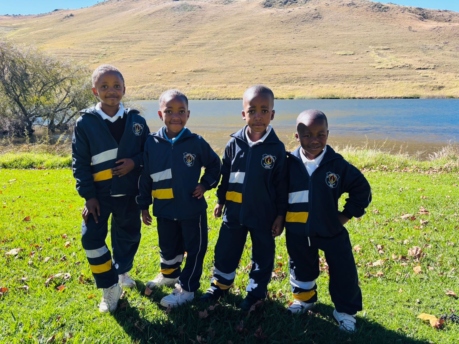 Four learners in navy and yellow school tracksuits